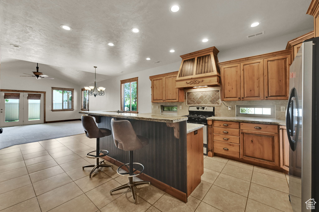 Kitchen featuring stainless steel appliances, premium range hood, recessed lighting, decorative backsplash, and vaulted ceiling