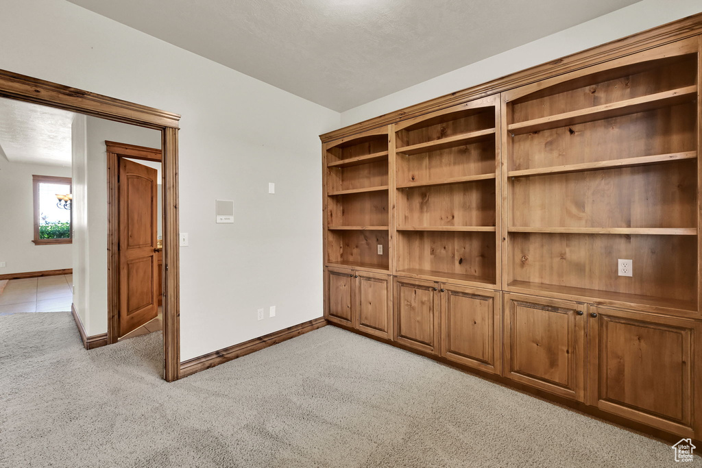 Unfurnished room featuring light carpet and baseboards