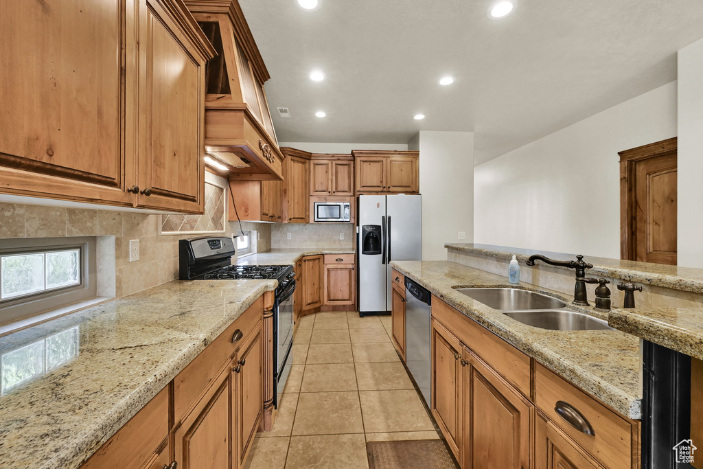 Kitchen featuring stainless steel appliances, backsplash, brown cabinets, light stone counters, and recessed lighting