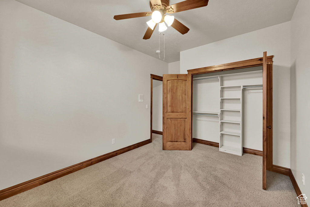 Unfurnished bedroom featuring light colored carpet, a closet, and ceiling fan