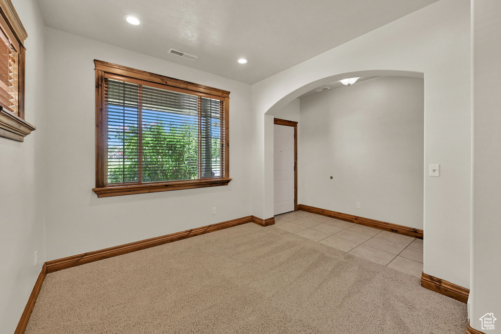 Spare room featuring arched walkways, light colored carpet, recessed lighting, and light tile patterned flooring