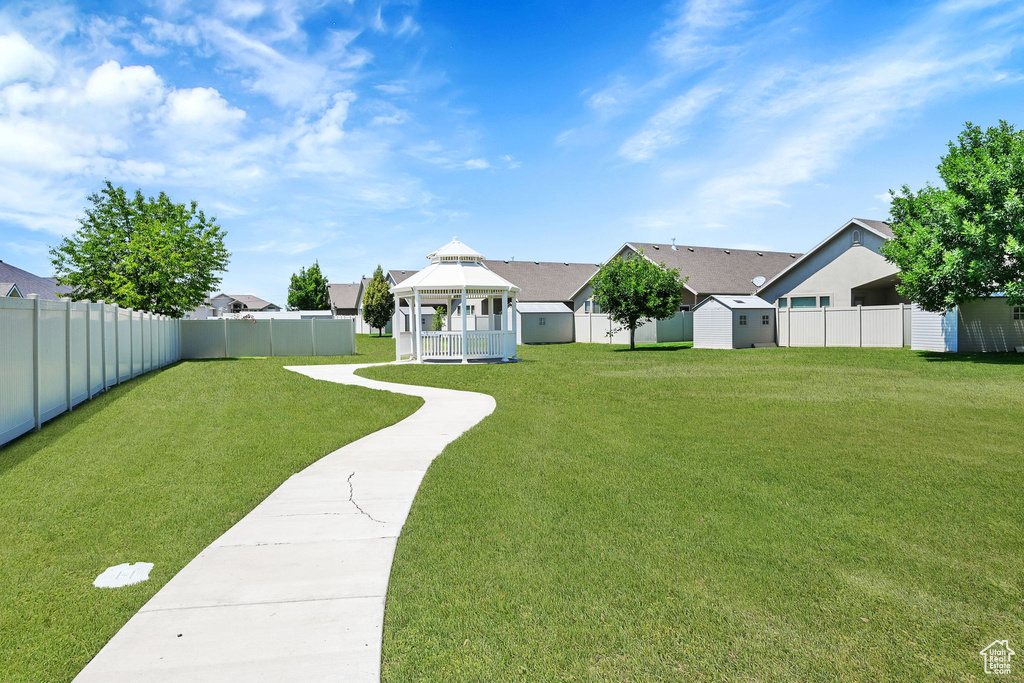 Fenced backyard featuring a gazebo, a storage shed, and a residential view