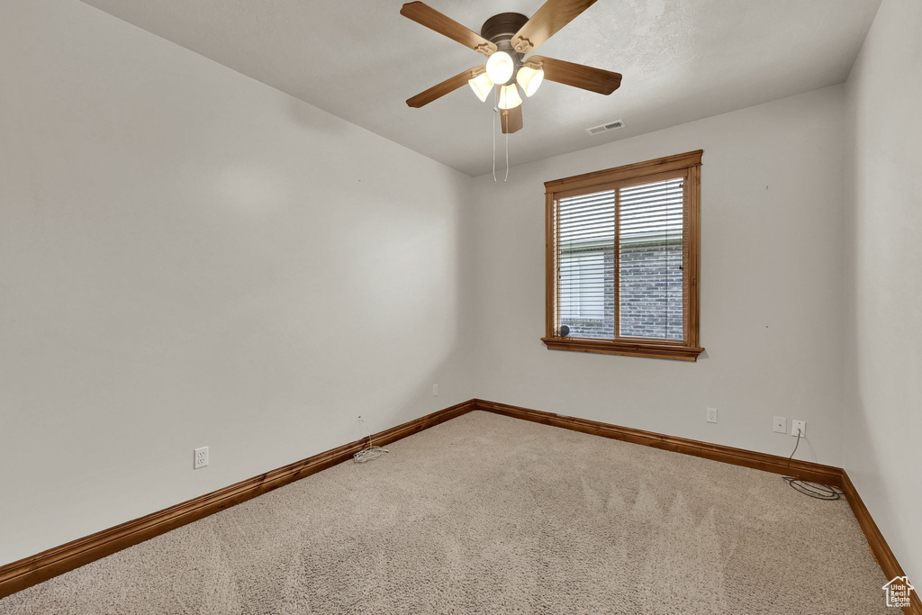 Spare room featuring carpet and ceiling fan