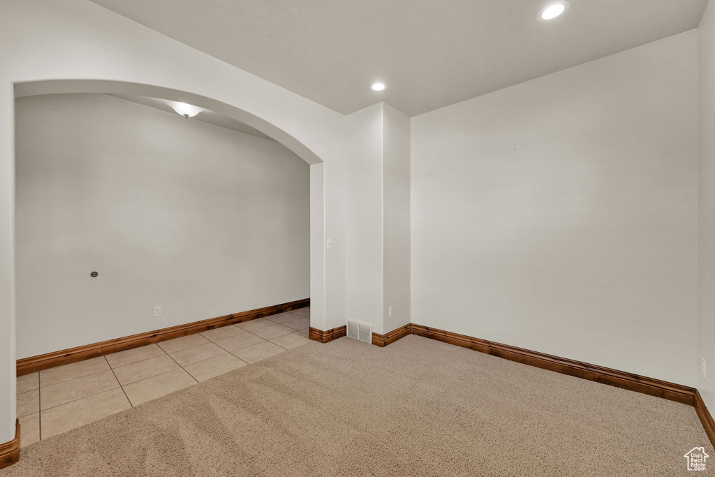 Spare room with arched walkways, light carpet, recessed lighting, and light tile patterned floors
