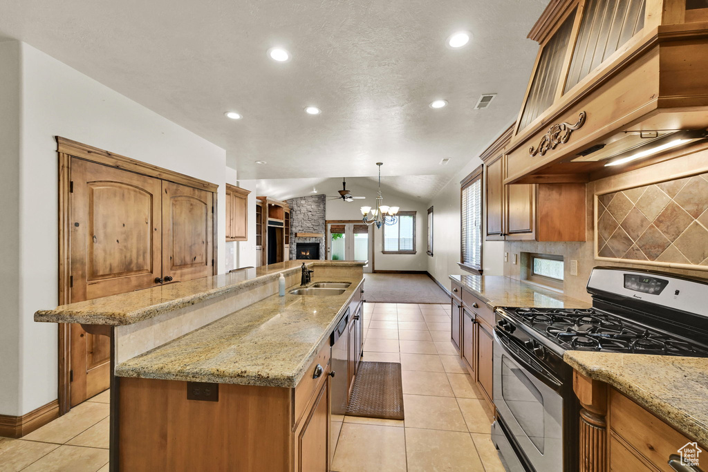 Kitchen featuring black range with gas stovetop, custom range hood, open floor plan, light tile patterned floors, and decorative backsplash
