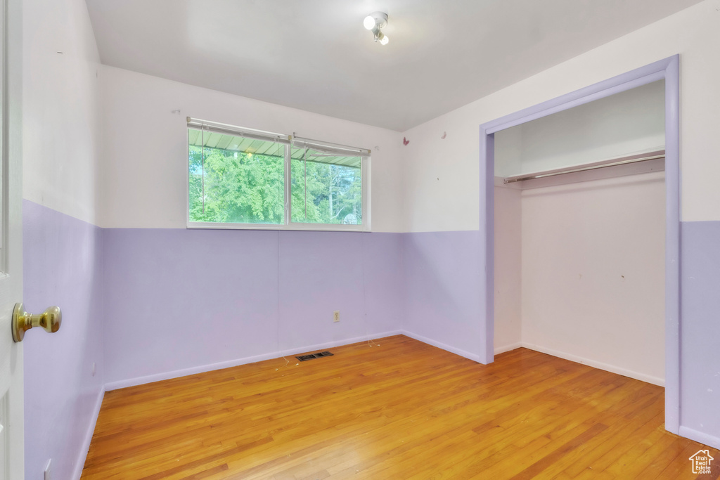 Unfurnished bedroom with light wood-style floors and a closet