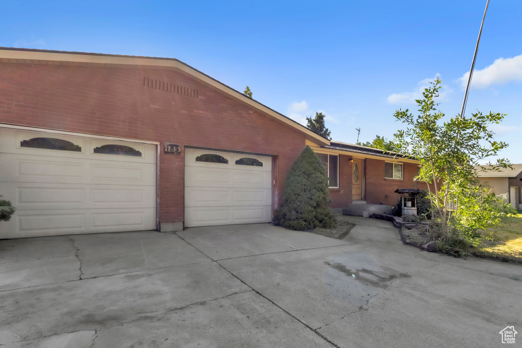 Single story home featuring a garage, driveway, and brick siding