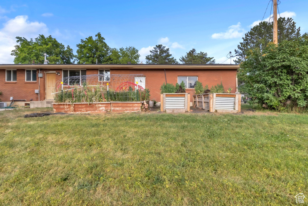 Ranch-style home featuring a vegetable garden, brick siding, and a front yard