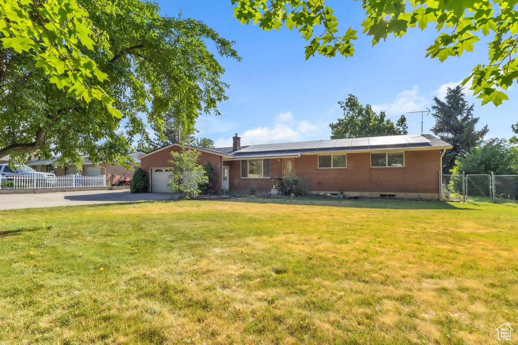 Single story home featuring a garage, driveway, a chimney, a gate, and solar panels
