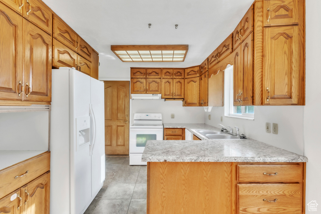 Kitchen featuring white appliances, under cabinet range hood, a peninsula, and light countertops