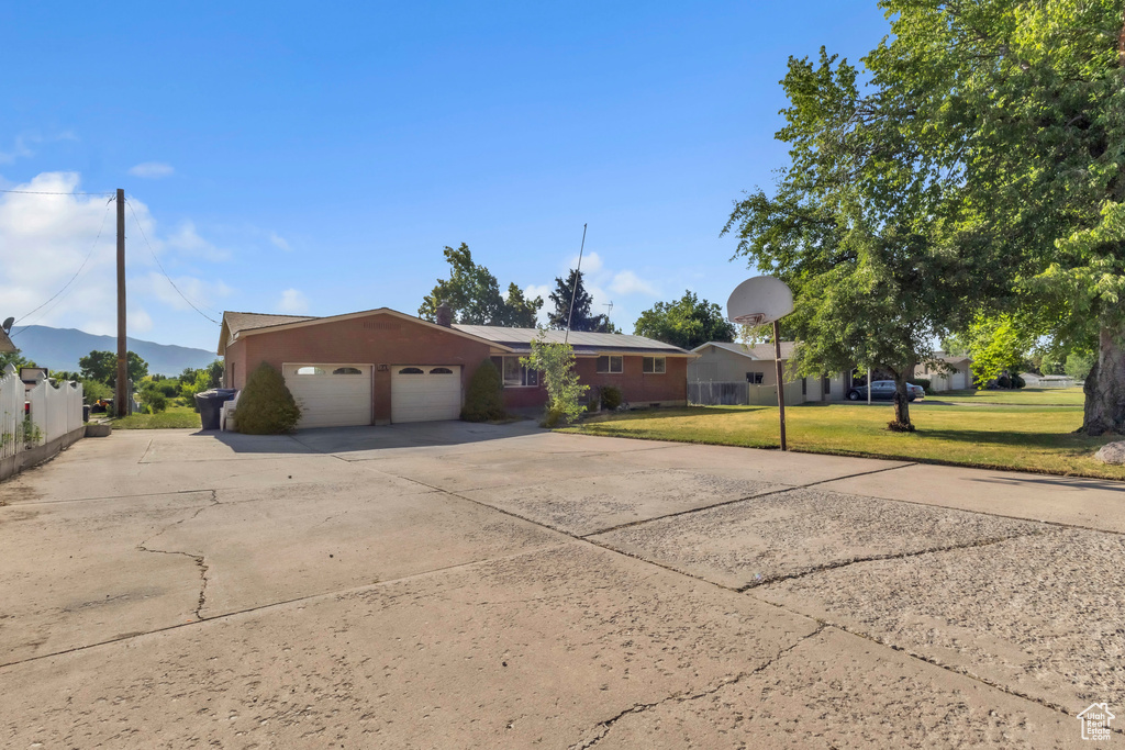 Ranch-style home featuring a garage, a front yard, and driveway