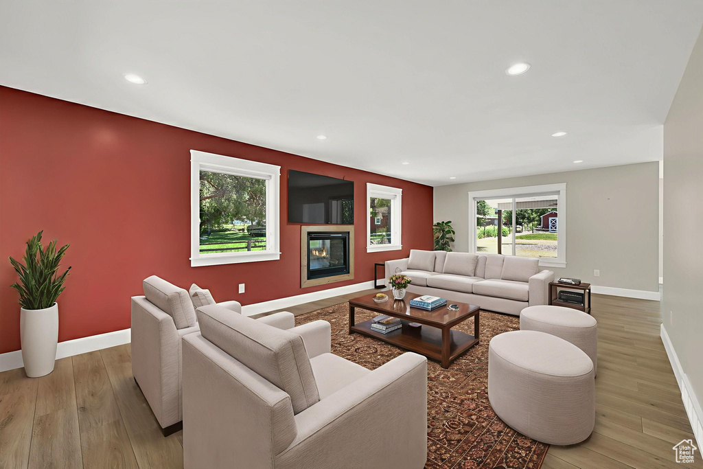 Living area featuring light wood finished floors, recessed lighting, and a glass covered fireplace