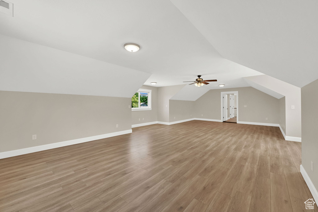 Additional living space with light wood-type flooring, a ceiling fan, and lofted ceiling