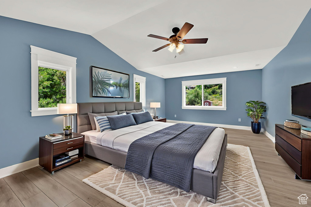 Bedroom with light wood-style floors, vaulted ceiling, and ceiling fan