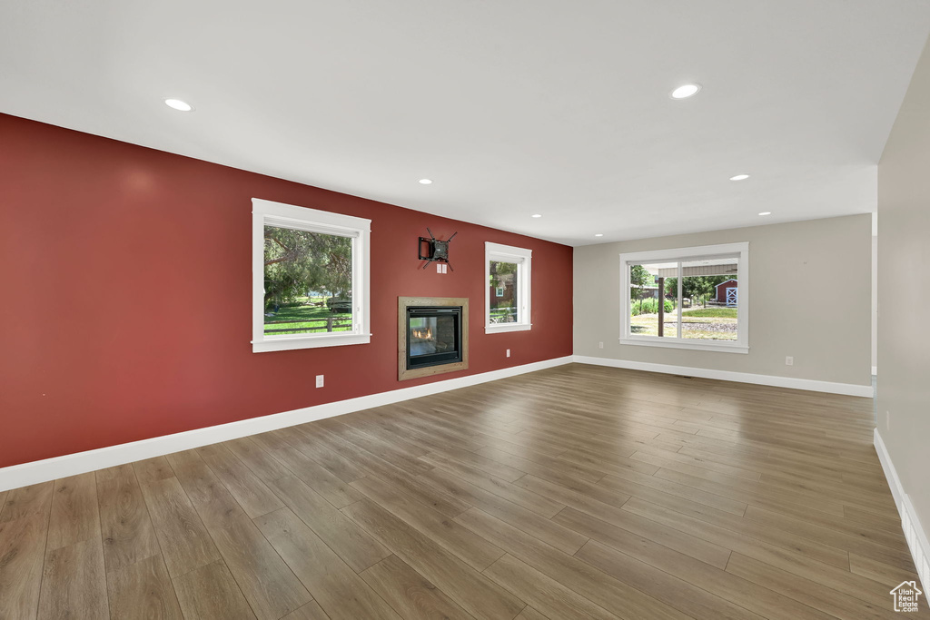 Unfurnished living room featuring wood finished floors, a glass covered fireplace, and recessed lighting