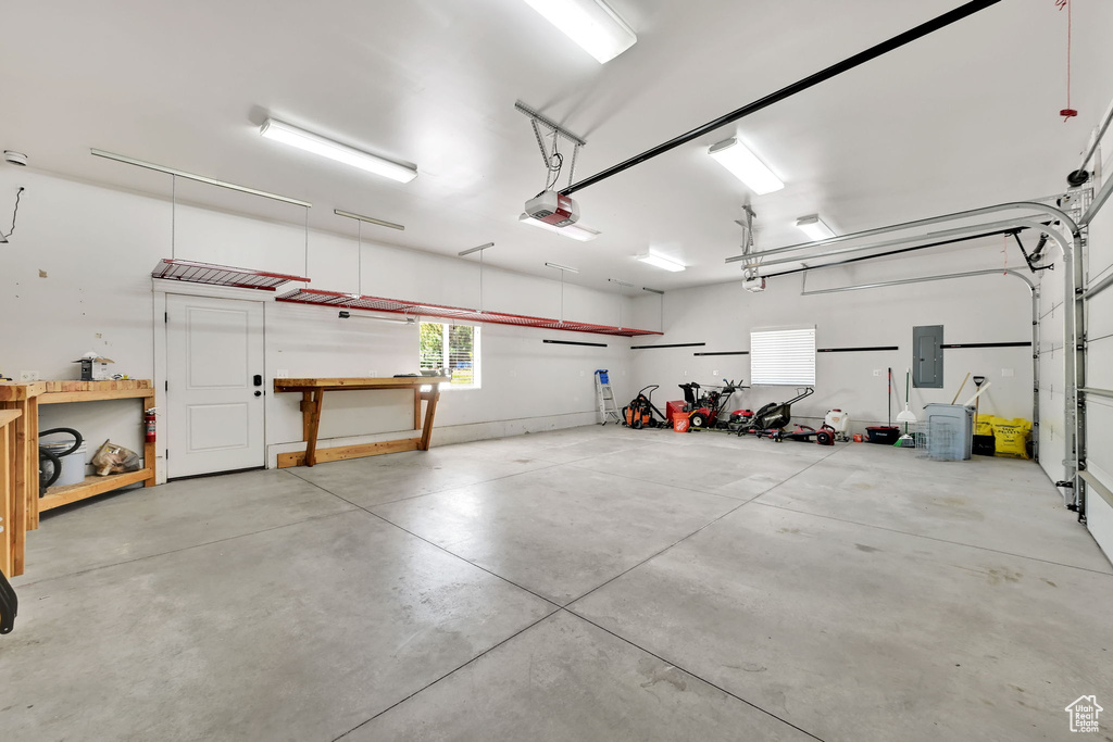 Garage with electric panel, a garage door opener, and a workshop area