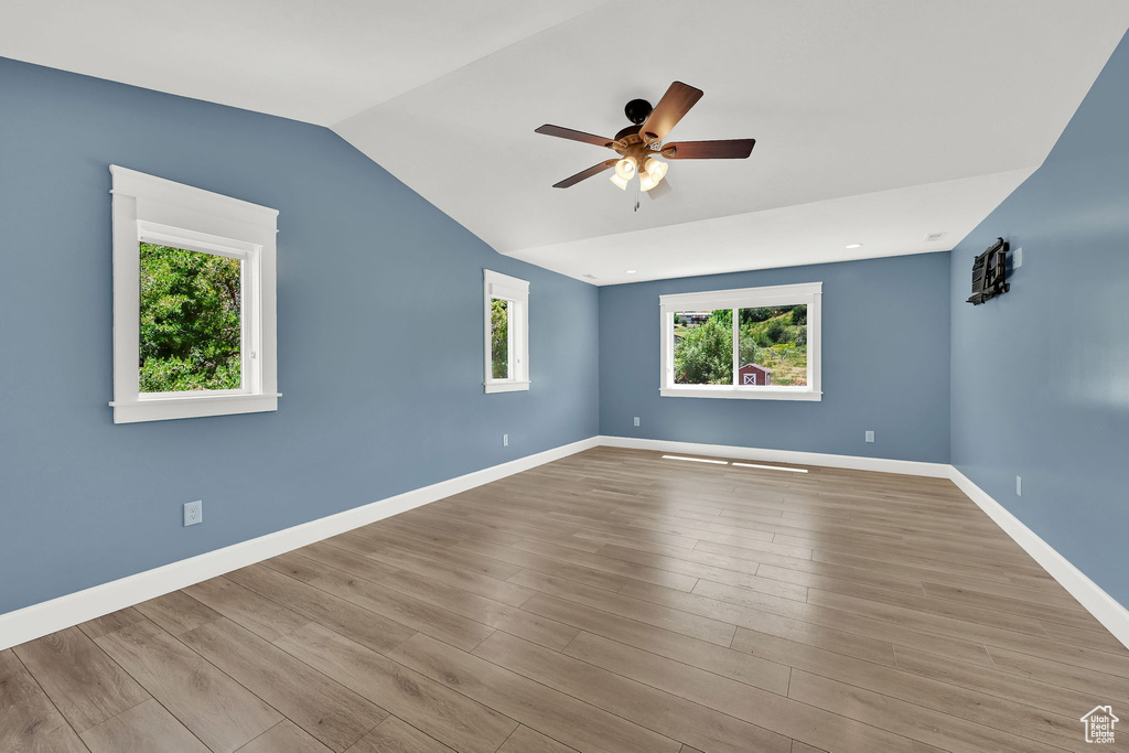 Spare room featuring a ceiling fan, lofted ceiling, and wood finished floors