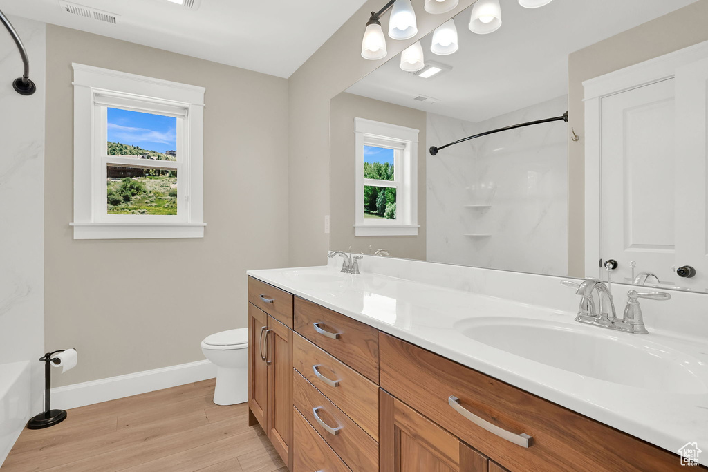Full bath featuring wood finished floors and double vanity