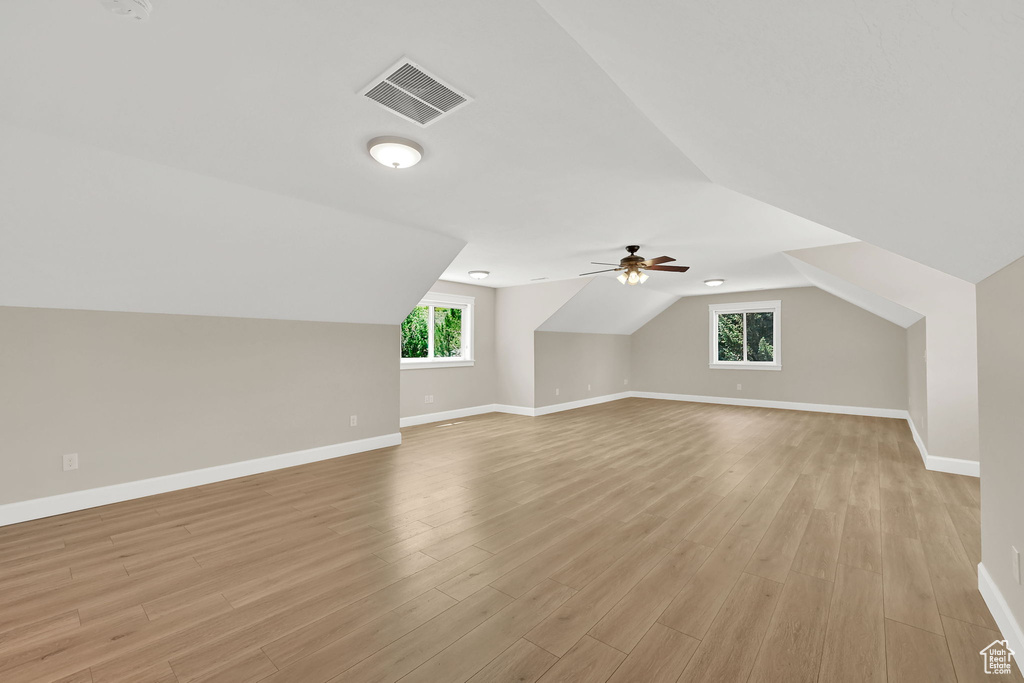 Bonus room with plenty of natural light, light wood-style floors, vaulted ceiling, and ceiling fan