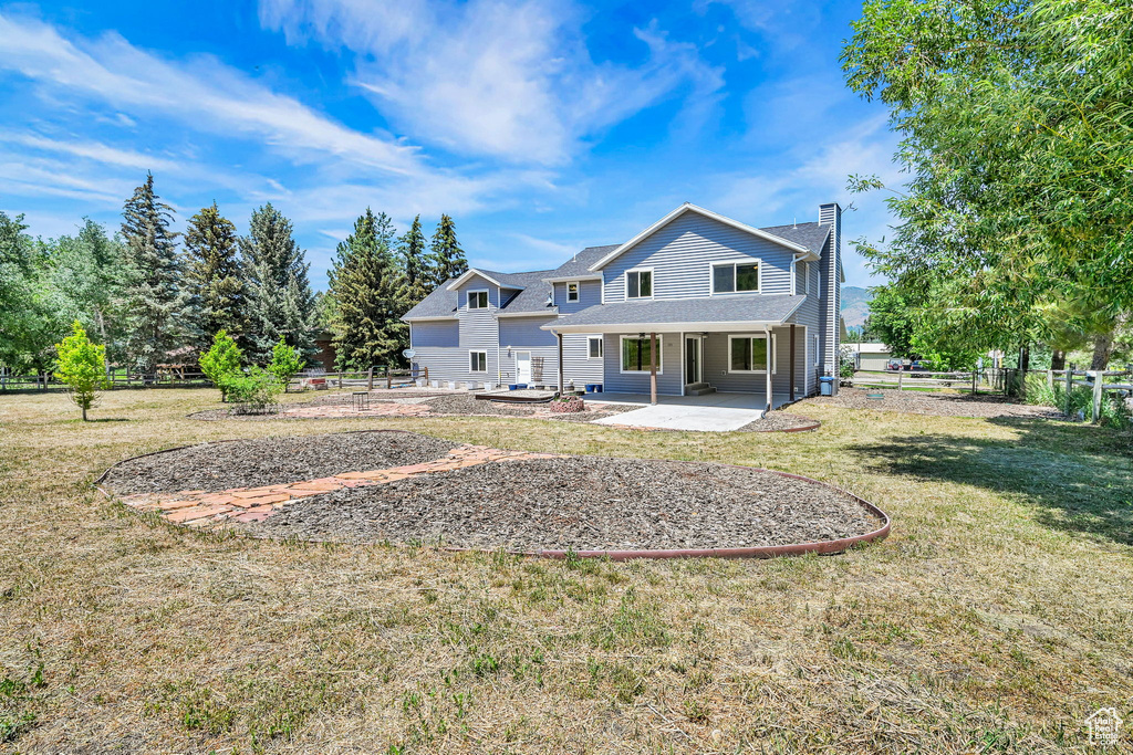 Back of house with a chimney, a patio, and a shingled roof