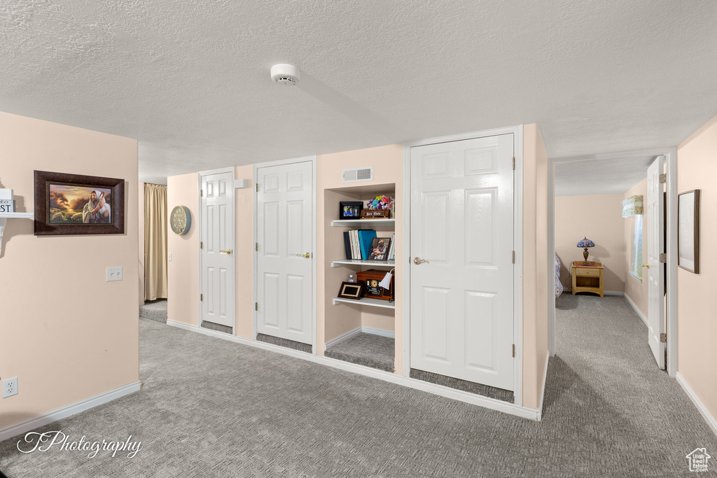 Hall featuring carpet flooring and a textured ceiling