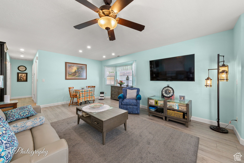 Living area with light wood-style floors, ceiling fan, and recessed lighting