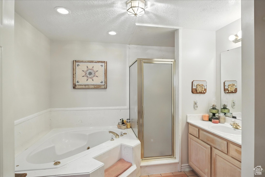 Bathroom featuring a textured ceiling, a shower stall, vanity, a jetted tub, and tile patterned floors