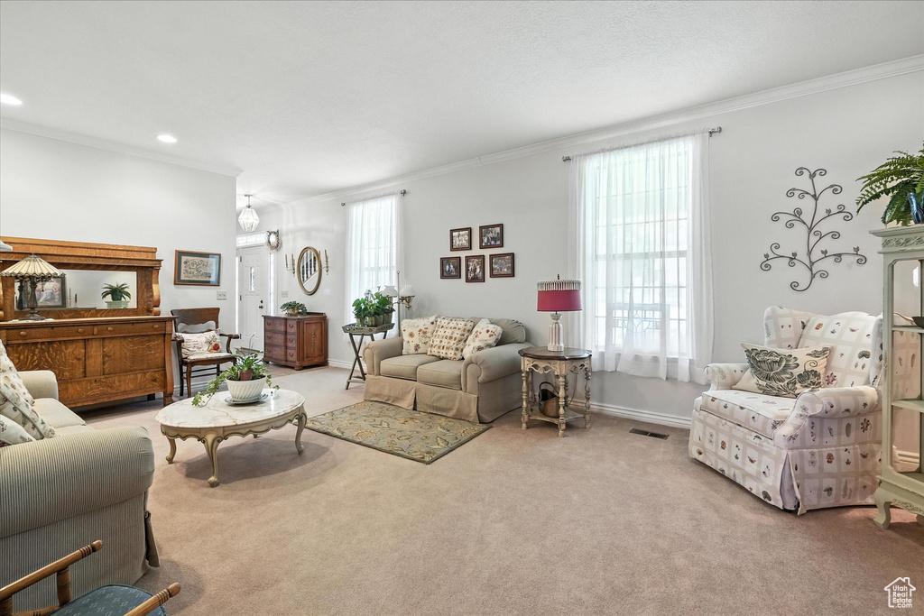 Carpeted living area with ornamental molding and recessed lighting