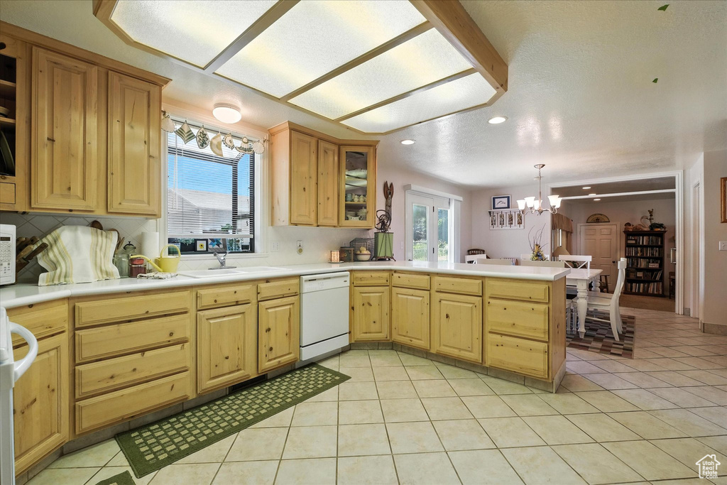 Kitchen featuring white dishwasher, a chandelier, a peninsula, plenty of natural light, and recessed lighting