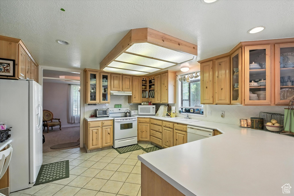 Kitchen with white appliances, light countertops, light tile patterned flooring, recessed lighting, and glass insert cabinets