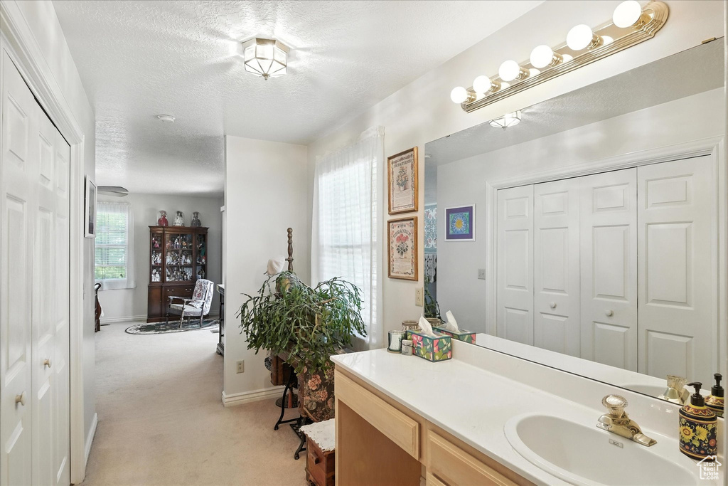 Bathroom featuring a closet, vanity, and a textured ceiling