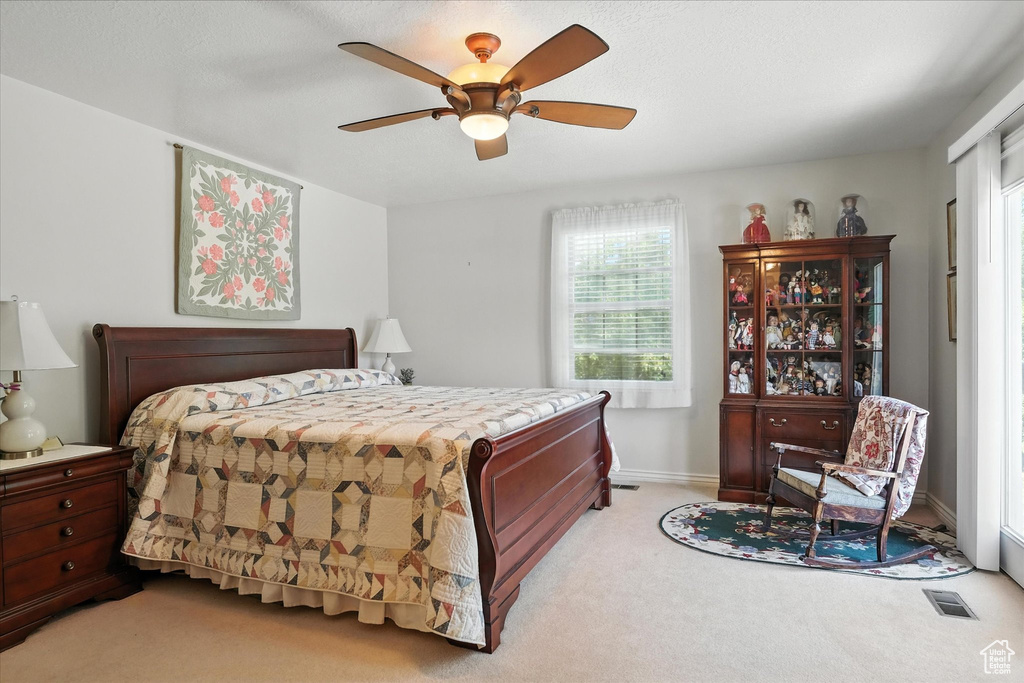 Bedroom with light colored carpet and a ceiling fan