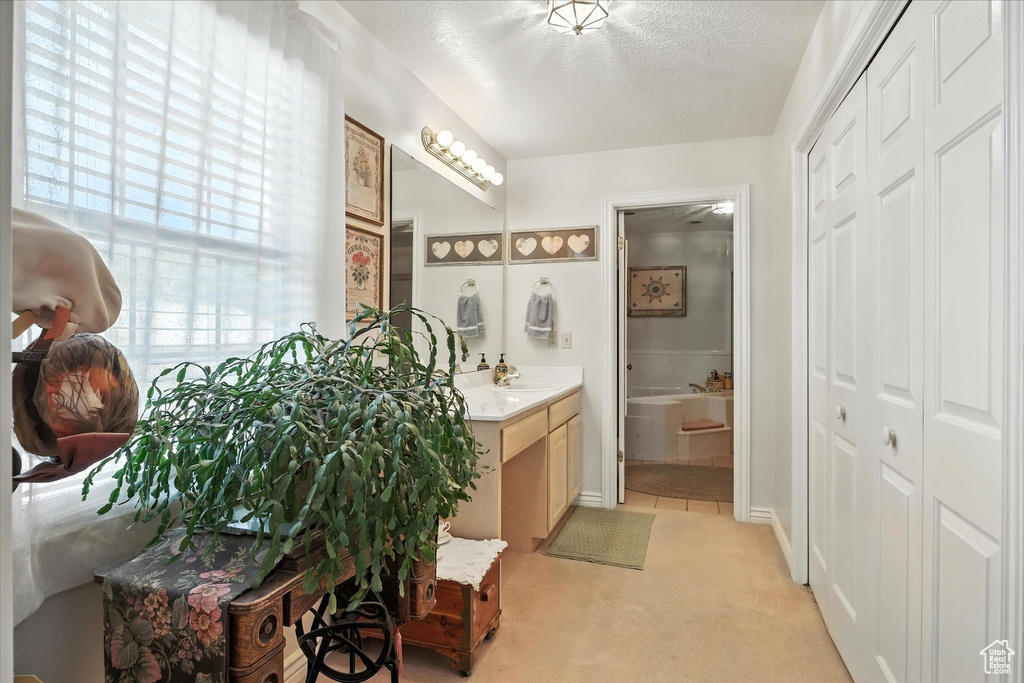 Full bath with vanity, a garden tub, a closet, and a textured ceiling