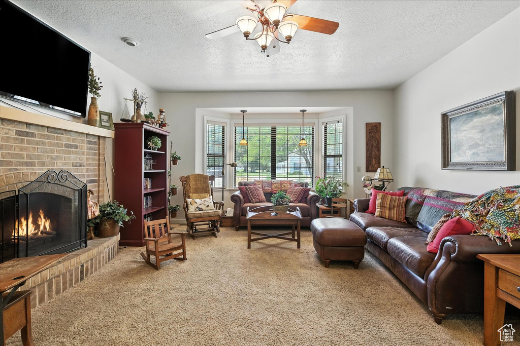 Carpeted living area featuring a textured ceiling, a ceiling fan, and a fireplace