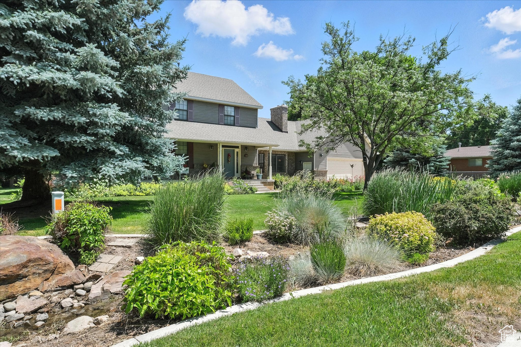 View of front of house featuring a chimney, a front yard, and covered porch
