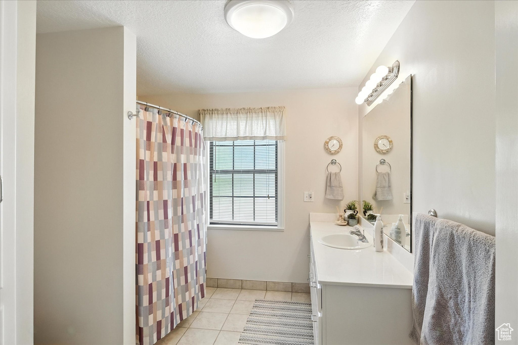 Full bathroom featuring vanity, tile patterned floors, a shower with shower curtain, and a textured ceiling