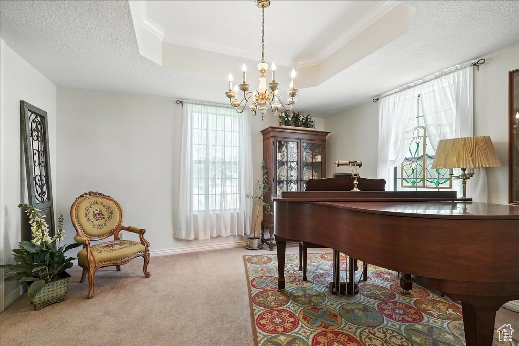 Living area featuring a chandelier, carpet flooring, a tray ceiling, and crown molding