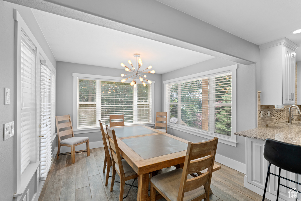 Dining area with plenty of natural light, light wood finished floors, and a chandelier
