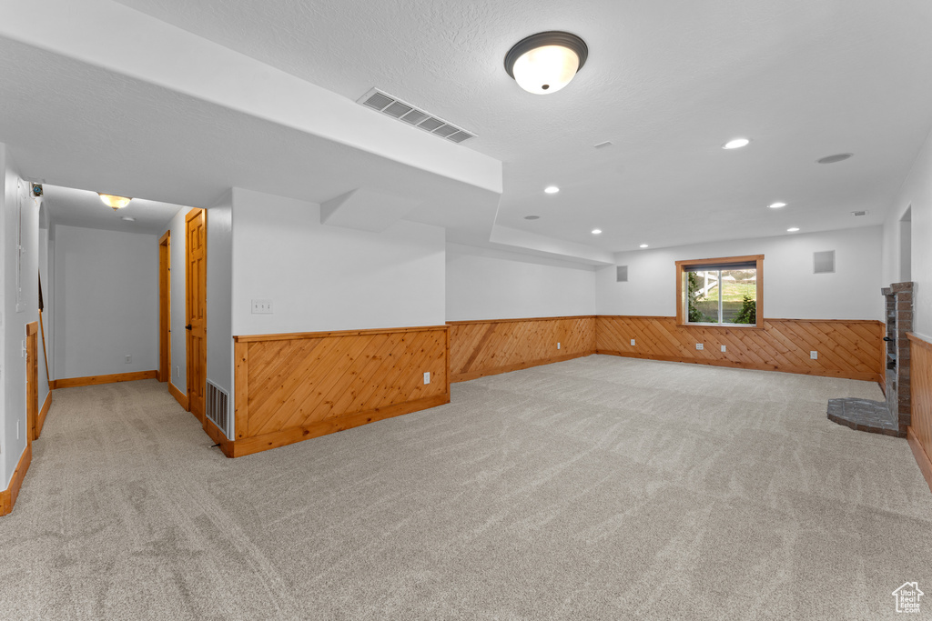 Basement with a wainscoted wall, wooden walls, carpet flooring, and recessed lighting