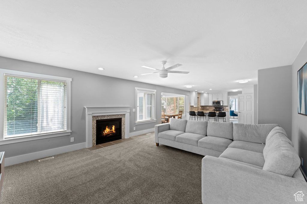 Living room with a fireplace with flush hearth, recessed lighting, ceiling fan, and carpet