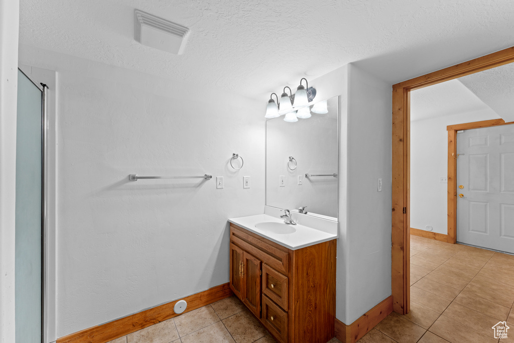 Full bath with vanity, tile patterned flooring, a textured ceiling, and a shower