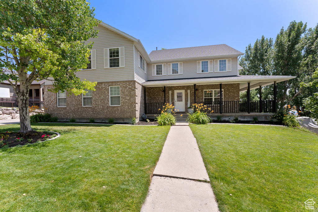 View of front of property featuring brick siding, a front yard, and covered porch