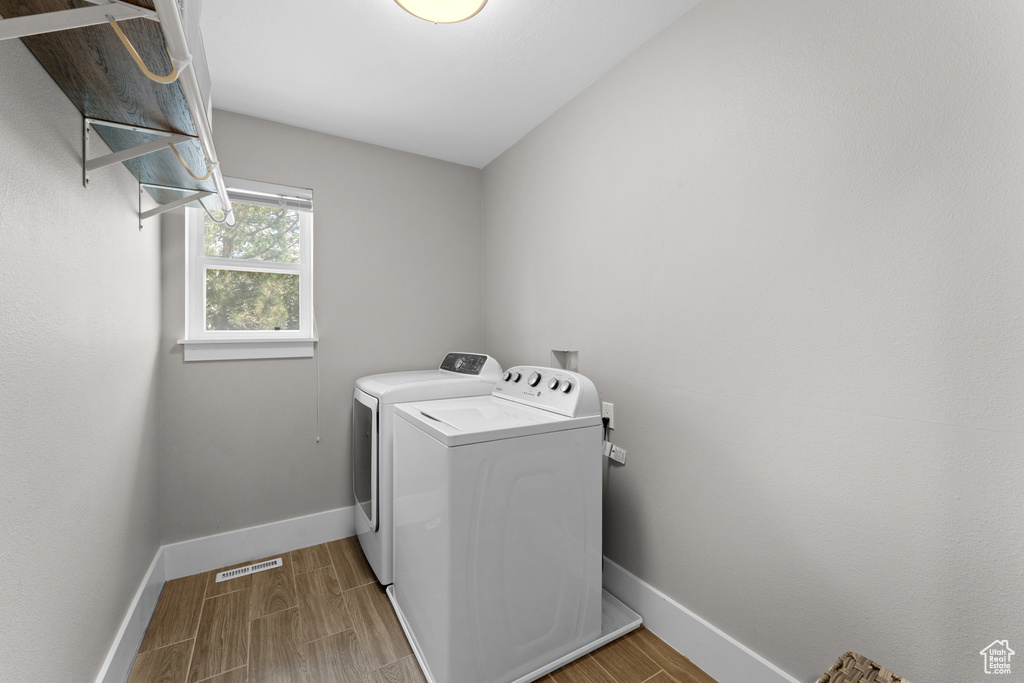 Washroom with washer and clothes dryer and wood finished floors