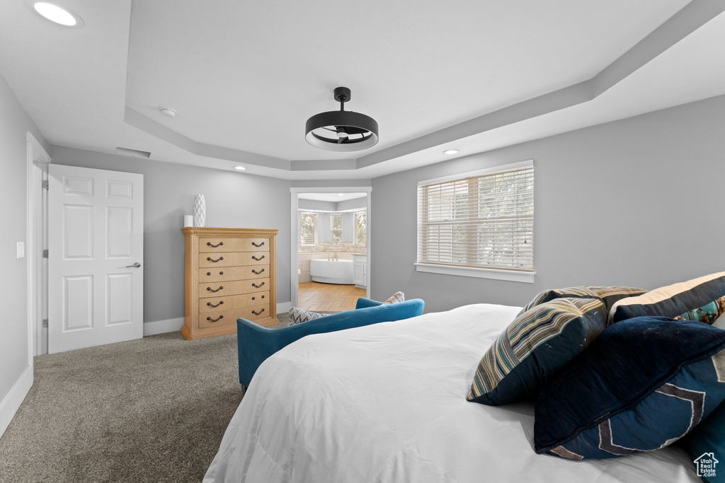 Bedroom featuring a raised ceiling, recessed lighting, carpet floors, and ensuite bathroom