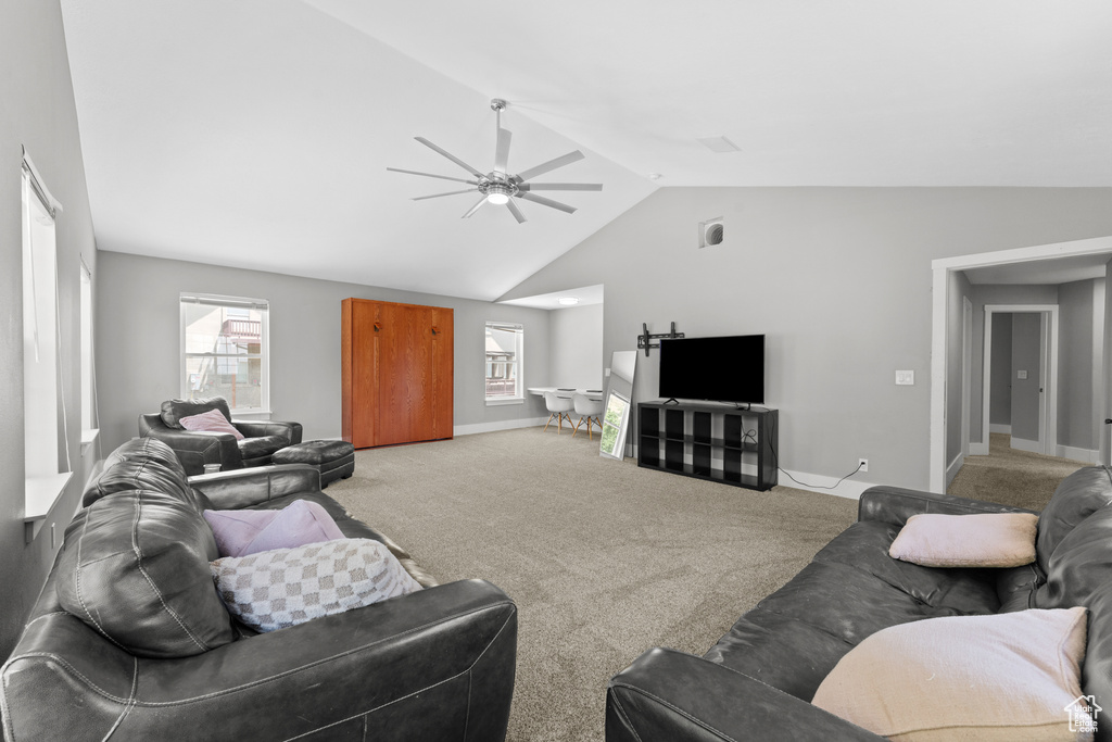 Living area with vaulted ceiling, a ceiling fan, and light carpet