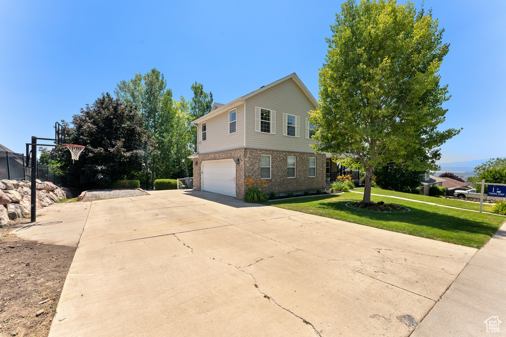 View of side of property featuring brick siding, a yard, a garage, and driveway
