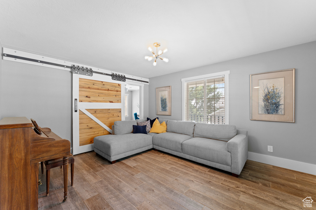 Living area featuring a barn door, wood finished floors, and a chandelier