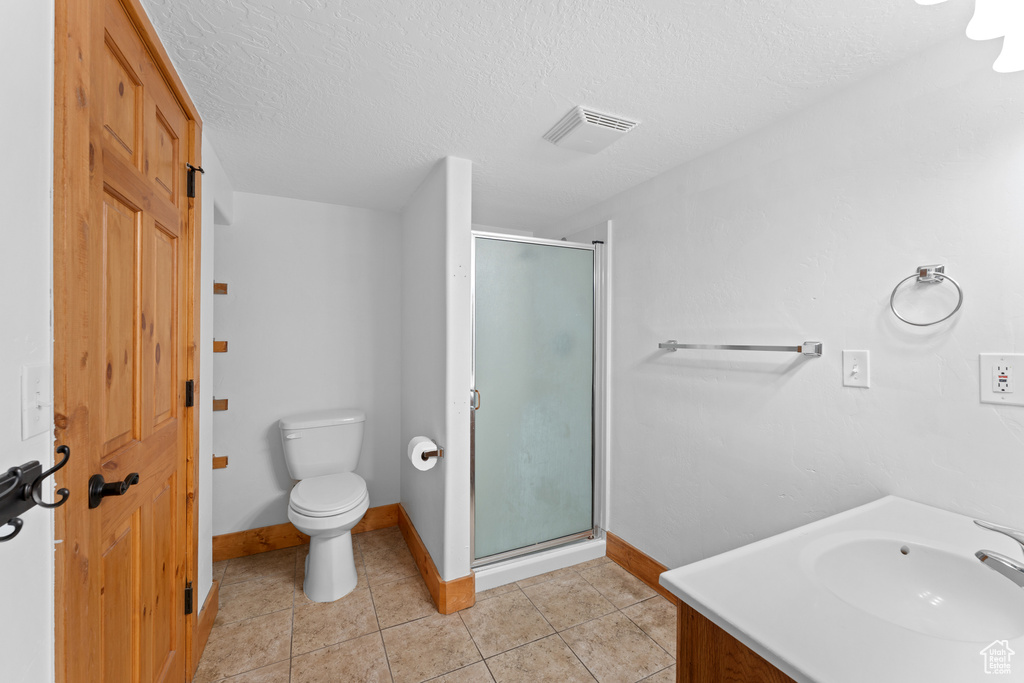 Bathroom with a shower stall, tile patterned floors, a textured ceiling, and vanity