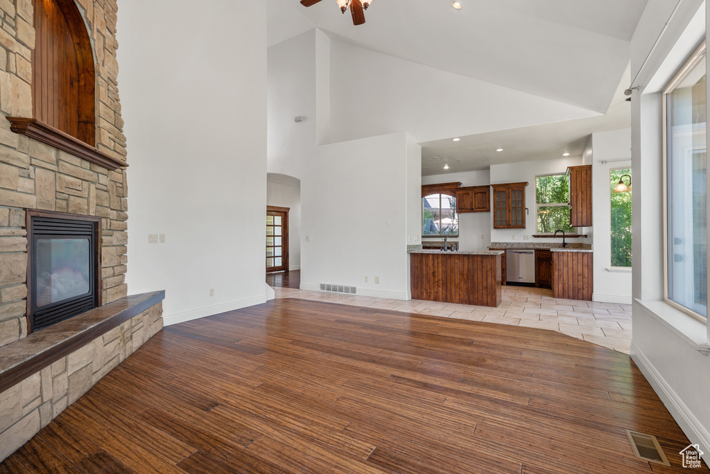 Unfurnished living room with a fireplace, recessed lighting, light wood-type flooring, a ceiling fan, and high vaulted ceiling