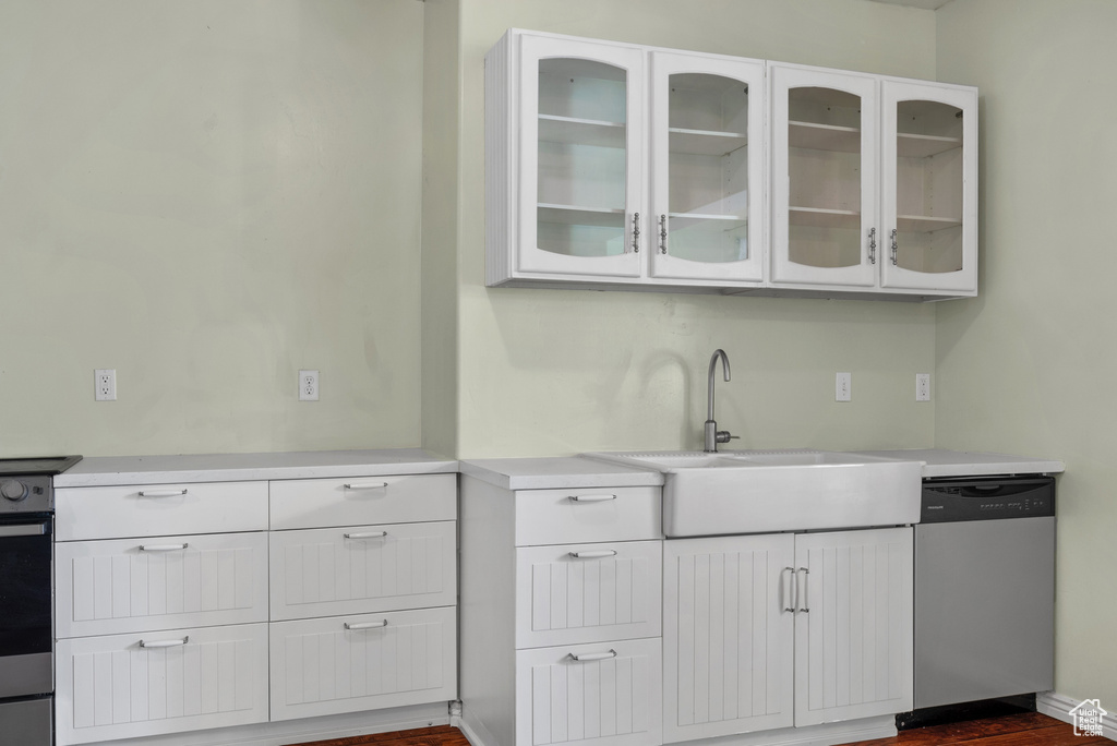 Kitchen featuring dishwasher, light countertops, white cabinets, and glass insert cabinets